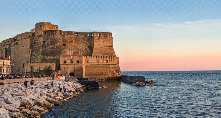 Une forteresse côtière avec un rivage rocheux au coucher du soleil.