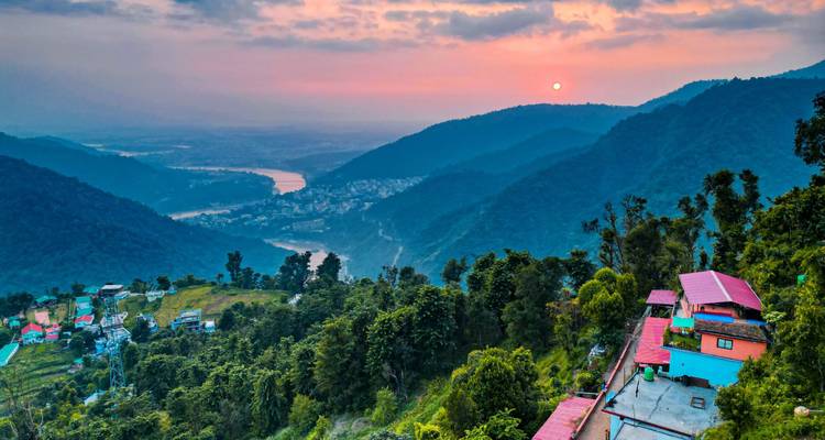 Collines vertes avec une rivière au coucher du soleil.