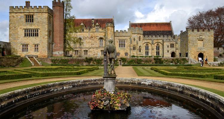 Château historique avec jardins et une fontaine.