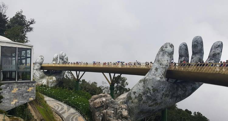 Los visitantes caminan por el icónico Puente Dorado de Da Nang sostenido por manos gigantes de piedra entre la niebla.