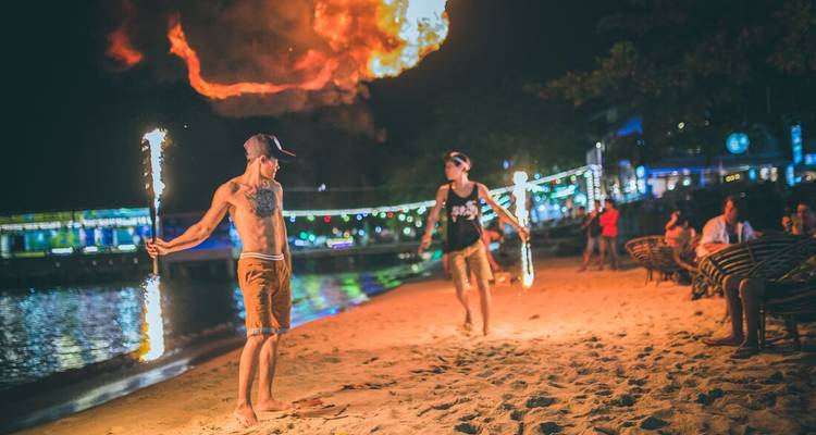 Fire show on a beach at night with performers twirling flames.