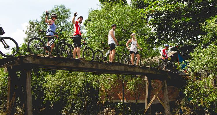 Group of cyclists posing on a wooden bridge.