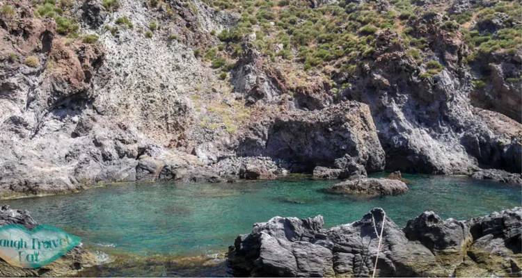 Línea costera rocosa con agua de mar y marca de agua de texto superpuesta.
