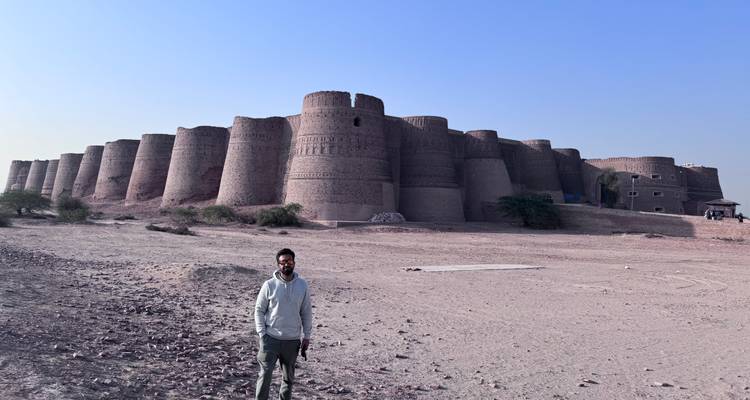 Voyageur se tenant devant les bastions massifs d'un fort désertique sous un ciel dégagé