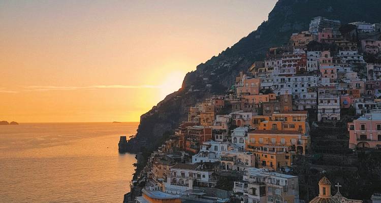 Ville côtière pittoresque sur une falaise escarpée au coucher du soleil.