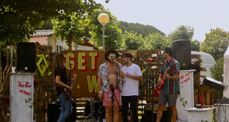 Musiciens jouant sur une scène extérieure avec un public.