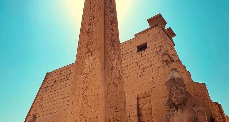 Temple égyptien antique avec un obélisque proéminent et un ciel bleu.