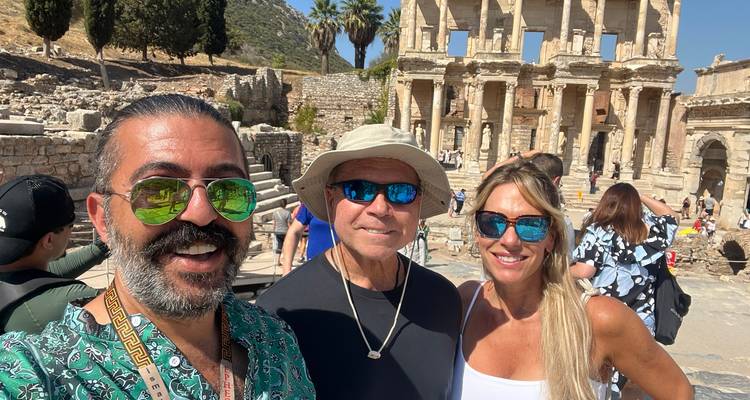 Trois personnes prennent un selfie devant des ruines antiques.