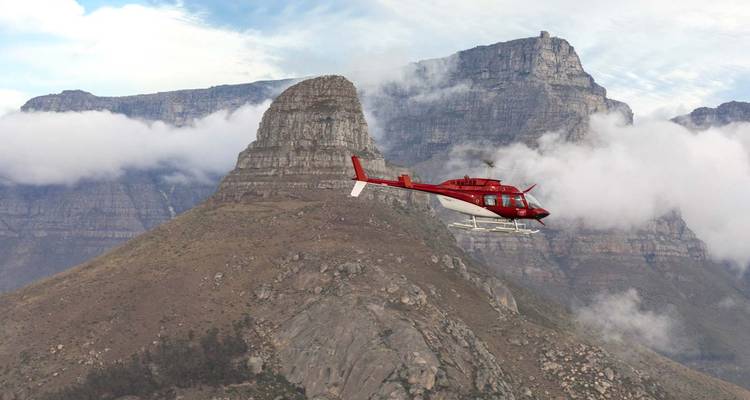 Hélicoptère volant près d'une montagne avec des nuages bas.
