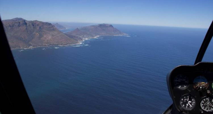 Vue de la côte et de l'océan depuis le cockpit d'un hélicoptère.