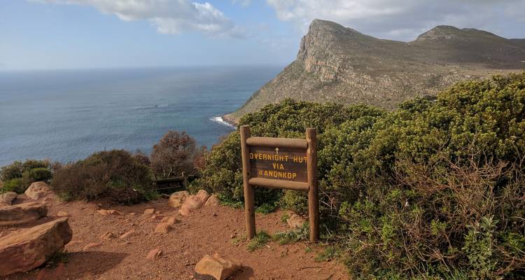 Vue panoramique du littoral avec panneau indiquant un refuge de randonnée.