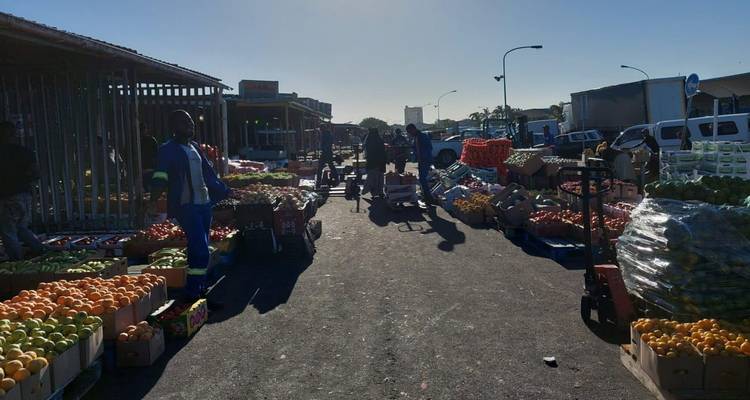 Marché en plein air avec fruits et légumes sous la lumière du matin.
