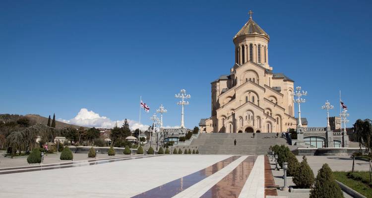 Vaste parvis menant à la Cathédrale de la Sainte-Trinité (Sameba) en pierre rose sous un ciel bleu dégagé