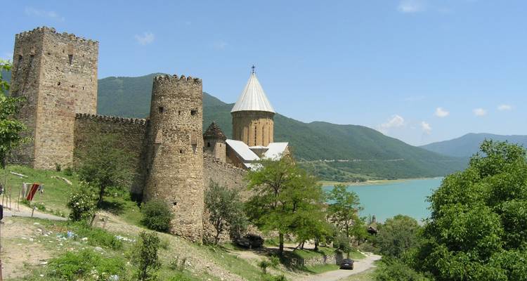 Les tours de la forteresse de pierre d'Ananuri s'élèvent au bord d'un lac turquoise encadré par les contreforts boisés du Caucase