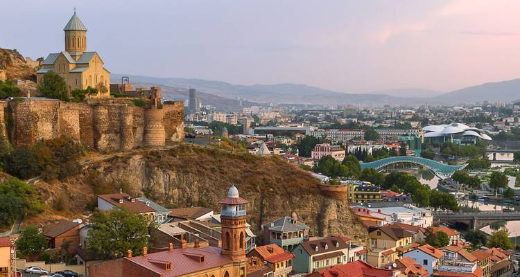Vue du coucher de soleil sur Tbilissi avec la forteresse de Narikala, l'église et les toits colorés s'étendant dans la vallée