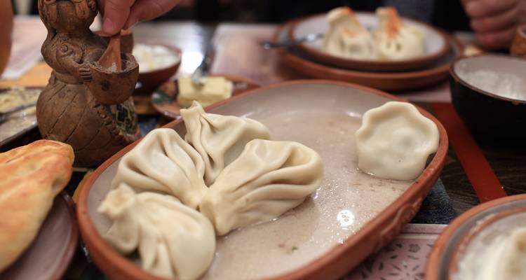 Les raviolis géorgiens traditionnels (khinkali) disposés sur une assiette en céramique rustique dans un restaurant local