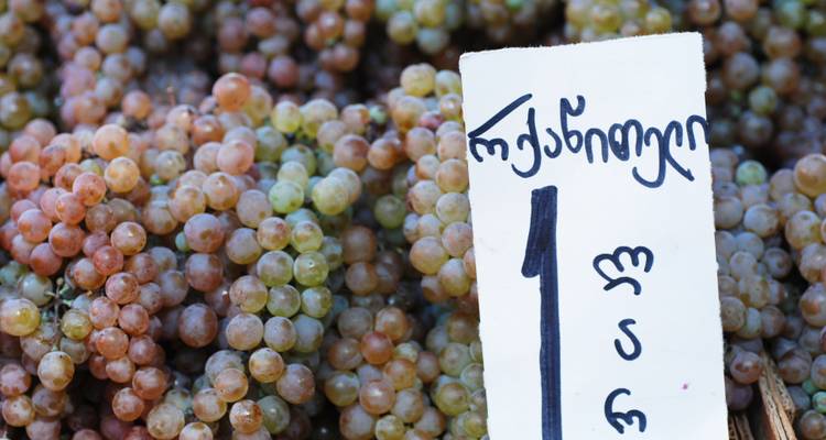Gros plan de raisins frais à vendre sur un marché avec un panneau de prix manuscrit géorgien