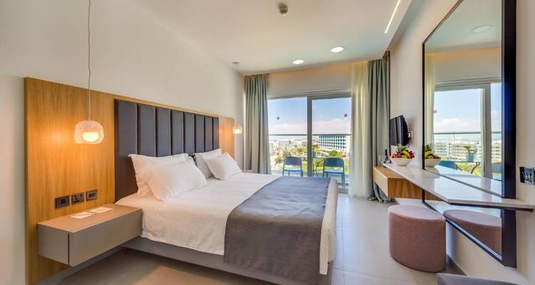 Chambre d'hôtel avec un grand lit, un mobilier moderne et une vue sur un balcon.