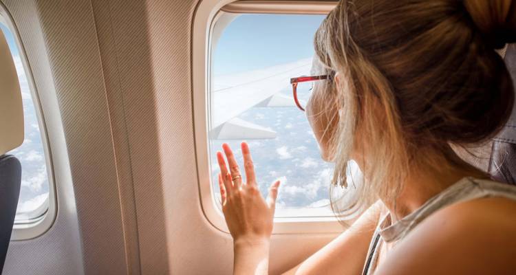 Person looking out of an airplane window at the sky.