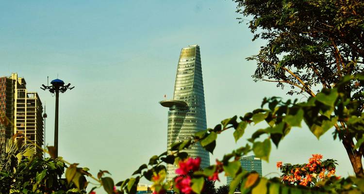 Modern skyscraper amidst foliage and urban environment.