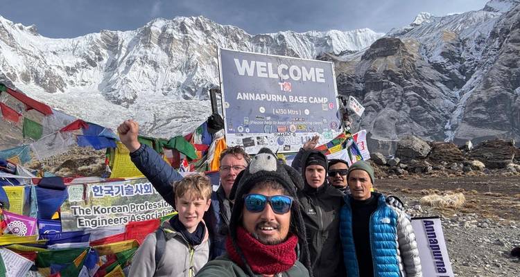Des personnes prenant un selfie au camp de base de l'Annapurna avec des montagnes enneigées en arrière-plan.