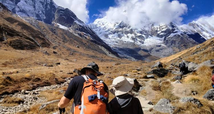 Deux randonneurs marchant à travers un paysage montagneux avec des sommets enneigés.