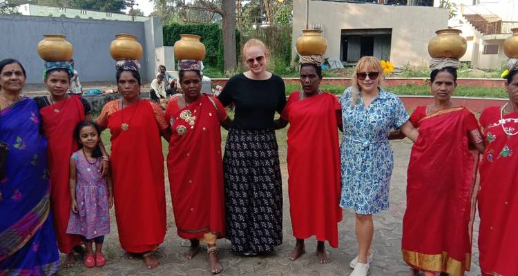 A group of women in traditional attire standing together outdoors.