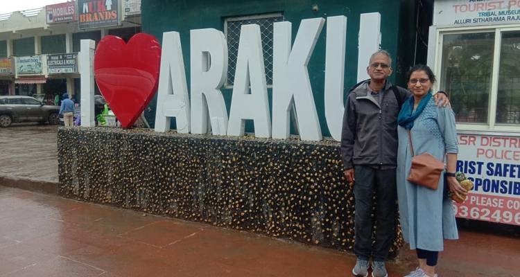 Two people posing next to a large sign that says 'I love Araku'.