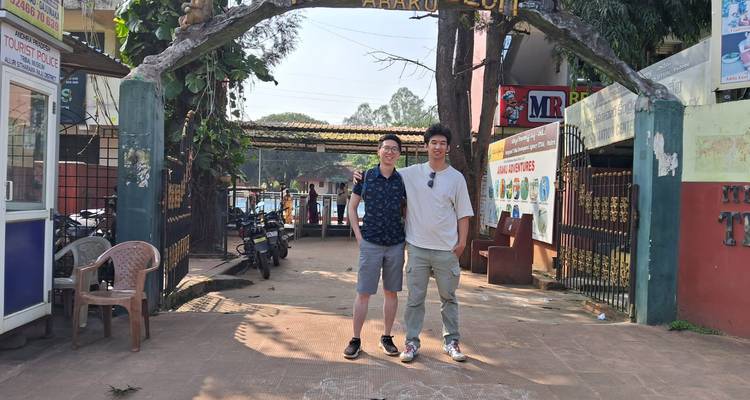 Two men standing under an archway that says 'Araku Coffee'.