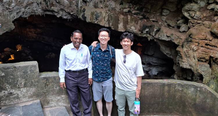 Three men standing at the entrance to a cave.