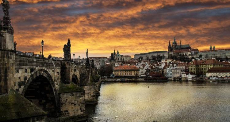 Prague's Charles Bridge and skyline during a vibrant sunset.