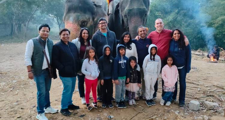 Un grupo de personas posando frente a dos elefantes.