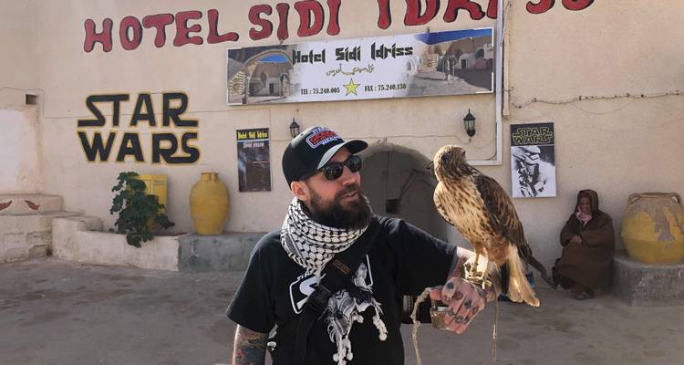 Homme tenant un faucon à l'extérieur d'un hôtel à thème.