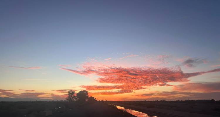 Atardecer vívido con nubes sobre un paisaje tranquilo.