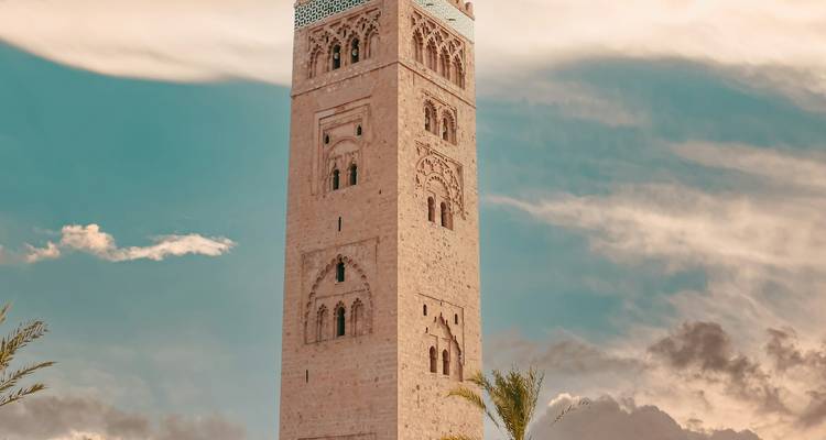 Gran torre de piedra bajo un cielo vibrante con palmeras.