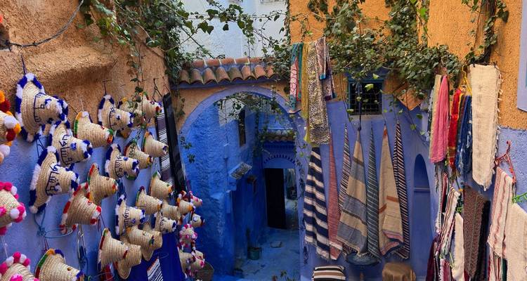 Ruelle étroite avec des murs bleus vibrants et des textiles suspendus.