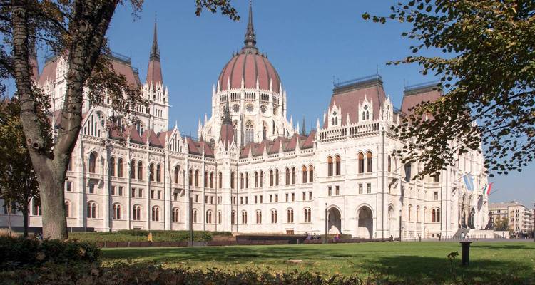 Gran fachada arquitectónica del Edificio del Parlamento Húngaro con árboles en otoño.