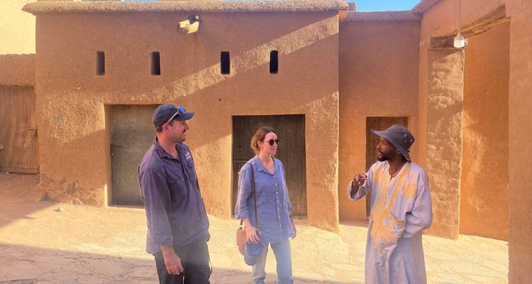Trois personnes ayant une discussion dans un bâtiment traditionnel en briques de terre.