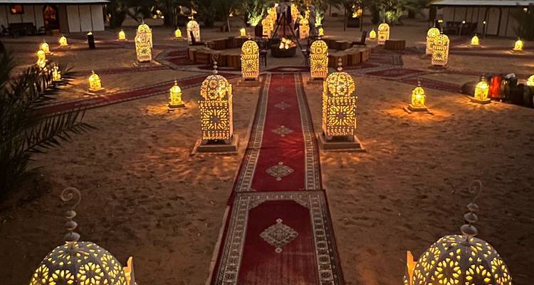 Vue nocturne d'un campement désertique magnifiquement éclairé avec des lanternes.