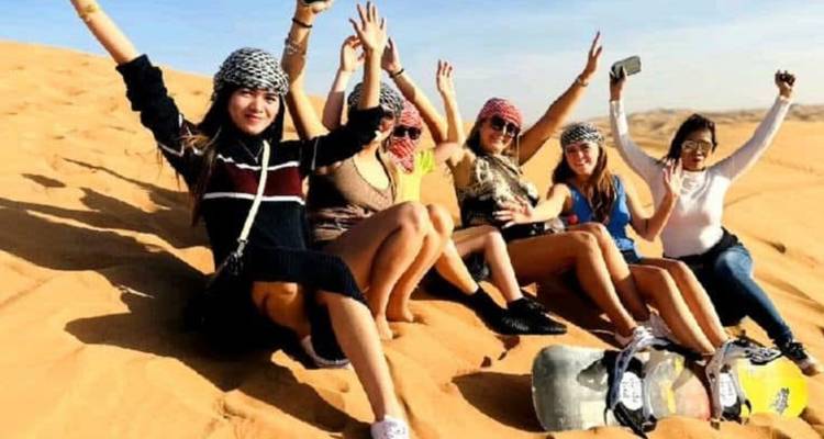 Groupe de personnes profitant des dunes de sable, tenant des planches à neige.