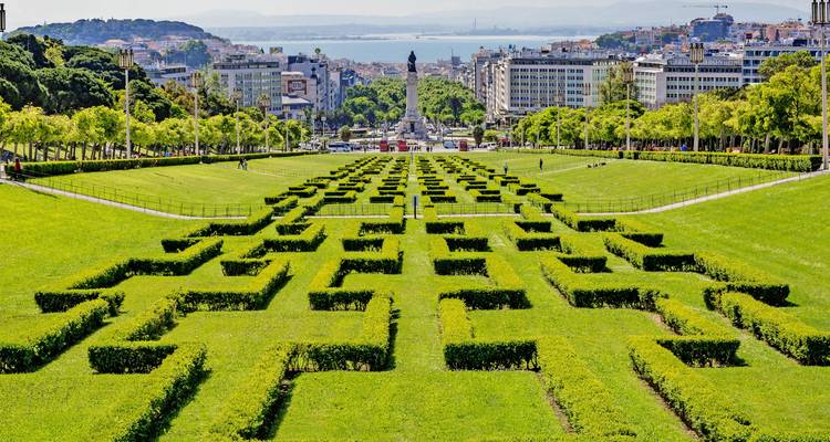 Parque with patrones geométricos de setos que conducen al horizonte urbano.