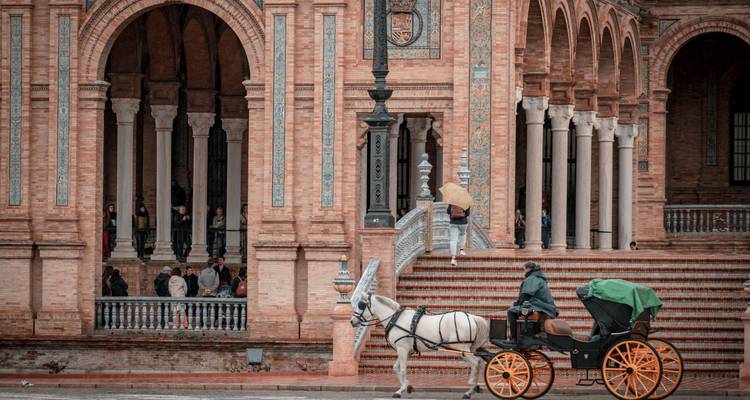 Horse-drawn carriage passing by a historic brick building.