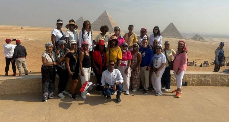 Groupe de personnes posant avec les pyramides de Gizeh en arrière-plan.