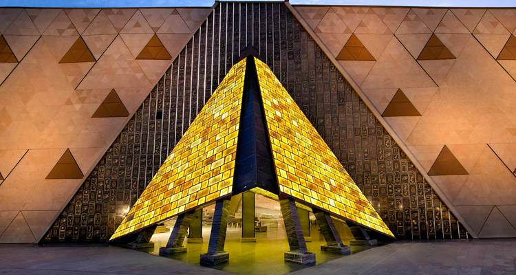 Architecture moderne avec une section triangulaire illuminée la nuit.