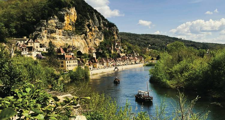 Malerisches Flussufer-Dorf mit Klippen und grüner Landschaft.