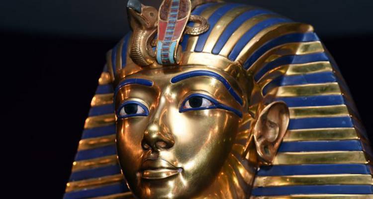 Le masque mortuaire en or du roi Toutânkhamon avec des accents bleus détaillés.