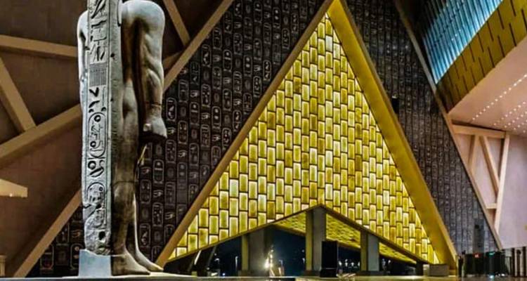 Intérieur du Grand Musée égyptien avec une statue antique et un design moderne.