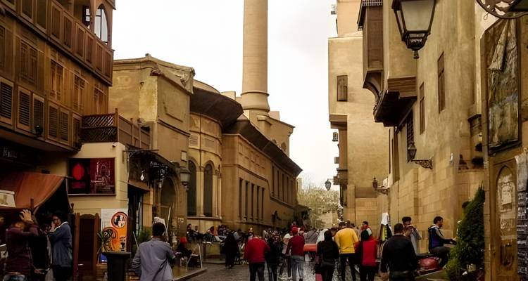 Rue bondée avec des bâtiments historiques et une tour de mosquée en arrière-plan.