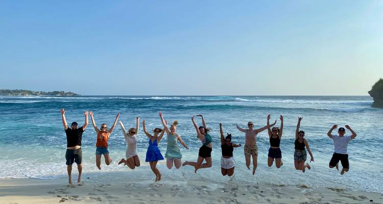 Groupe de personnes sautant à l'unisson sur une plage.