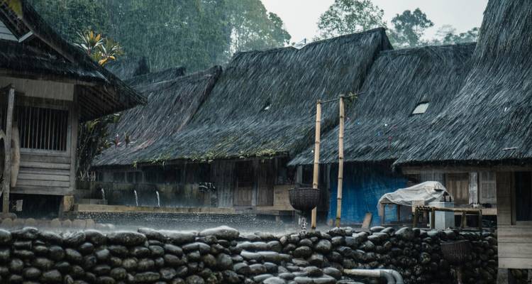 Casas tradicionales de madera con techos de paja bajo la lluvia.